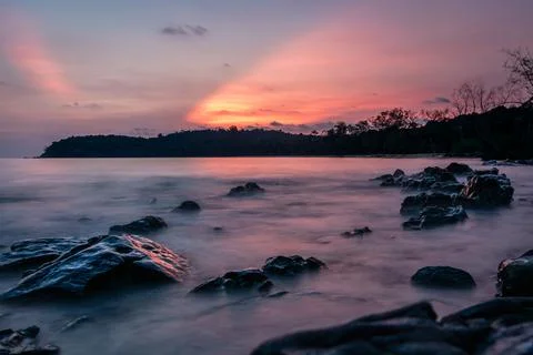 The sub bursts through the clouds in this coastal rocky long exposure of the  Stock Photos
