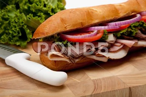 A sub sandwich on a wooden cutting board Stock Photos