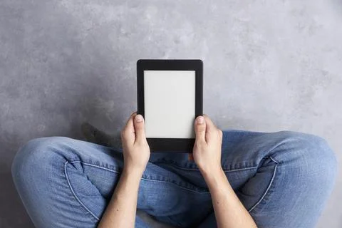 Subjective view of a young person reading a text on an electronic reader. Stock Photos