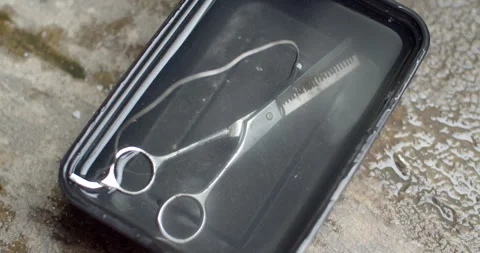 Submerging a rusted pair of scissors into saltwater to start the electrolysis. Stock Footage 312949607