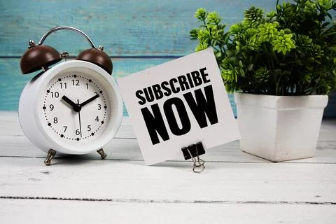 Subscribe Now  text written on paper card with alarm clock on wooden backgrou Stock Photos