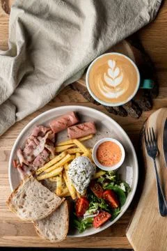 Substantial breakfast in a cafe with bacon, roasted sausage poached egg and s Stock Photos