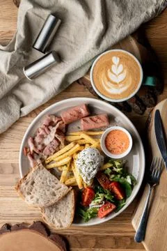 Substantial breakfast in a cafe with bacon, roasted sausage poached egg and s Stock Photos