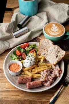 Substantial breakfast in a cafe with bacon, roasted sausage poached egg and s Stock Photos