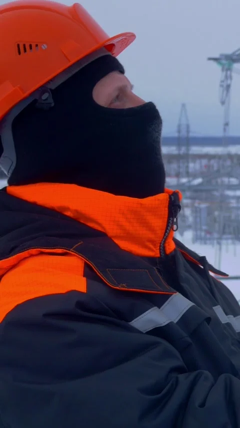 Substation worker in winter gear analyzing data. Snowy landscape underscores Stock Footage 278996424