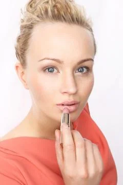Subtle makeup - blonde paints lips with lipstick  Stock Photos