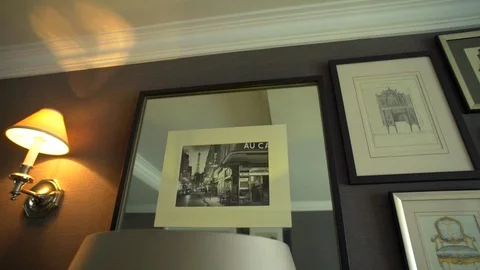 Subtle panning shot past mirrored picture frames and a lamp  on a wall 스톡 동영상 116108951
