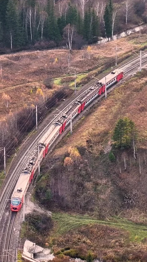 Suburban electric train passing a winding railway through autumn forest and.. Stock Footage 336944030