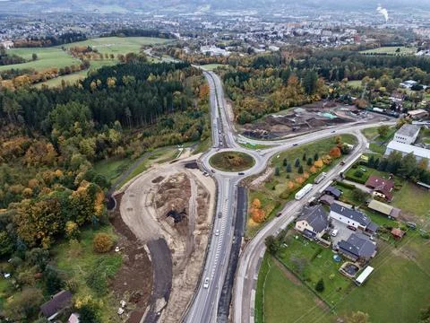 Suburban roundabout being built, engineer inspecting site amidst seasonal Stock Photos