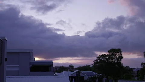 A suburban scene at dusk. Grey clouds fly overhead - time lapse Video stock 284205660