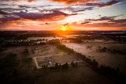 Suburban sunset view from above on fields and trees in line. Evening light. Stock Photos