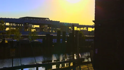 Subway run on elevated Station above the canal during sunset in Brooklyn, NYC Stock Footage 231509482