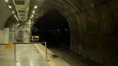 Subway station platform inside a dark concrete tunnel with train tracks running  Vídeo Stock 344116755