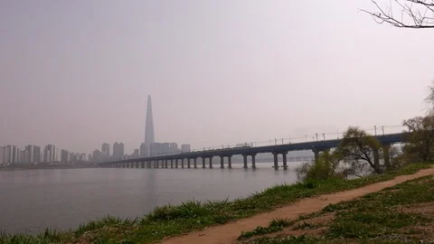 Subway train on bridge across Han river, panorama of Lotte World Tower in Stock Footage 94368407
