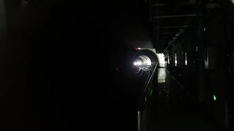 A subway train with bright headlights approaches through a dark, arched tunnel. Stock Footage 333451187