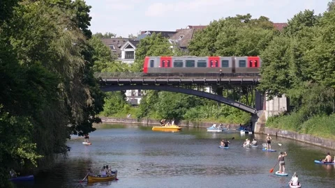 Subway Train Crossing Bridge Over Alster River with Paddleboarders in Hamburg Stock Footage 296058571