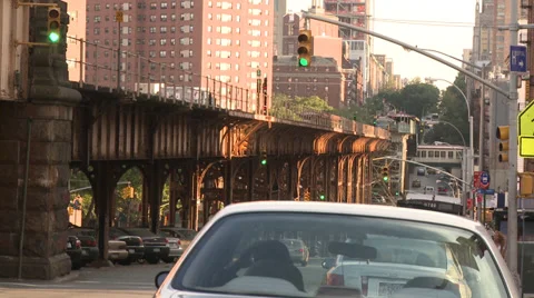 Subway train on elevated-level track above cars, cabs, street Stock Footage 39615358