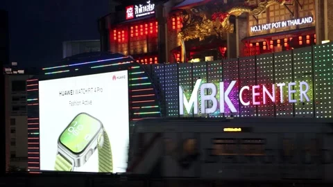 A subway train passes under a facade with colorful illuminated advertising Stock Footage 314463289