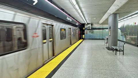 A subway train speeds past an empty station platform Stock Photos