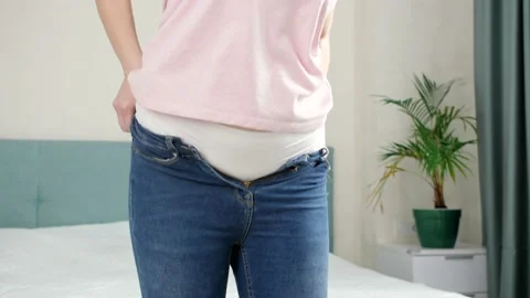Success in fitting and dressing in tight jeans. Concept of excessive weight Stock Footage 155772129