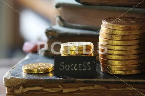 Success tag and Golden coins on the background of vintage books. Stock Photos