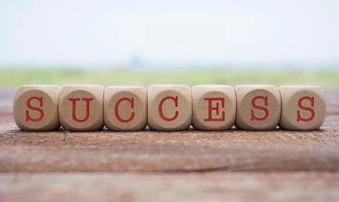 Success word written on cube shape wooden blocks on wooden table.  Stock Photos