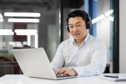 Successful asian programmer with laptop inside office, mature experienced man in Foto stock