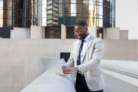 Successful Black Manager Using Computer In  Front OF Modern Office Buildings Stock Photos