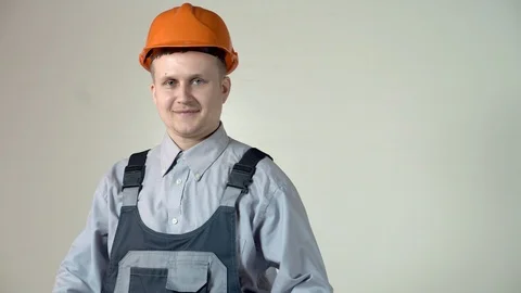 A successful builder engineer in an orange helmet on a grey background showing l Stock Footage 102777744