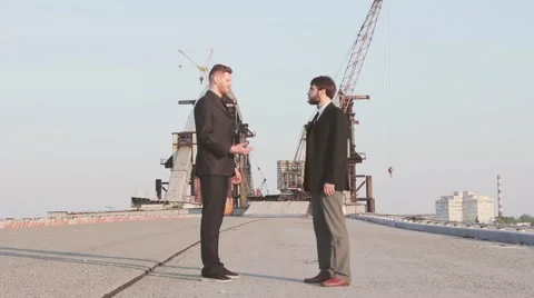 Successful business partners talk while standing at an industrial site and shaki Stock Footage 62872849