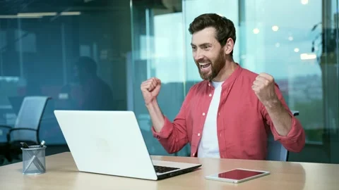 A successful businessman ecstatically celebrates a win as he looks at Stock Footage 234143661