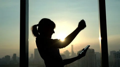Successful businesswoman with smartphone standing by window during sunset 스톡 동영상 59123777