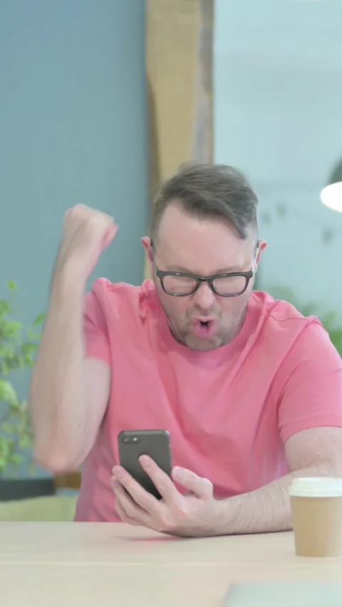Successful Creative Old Man Celebrating Win on Smartphone, vertical video Video stock 329106343