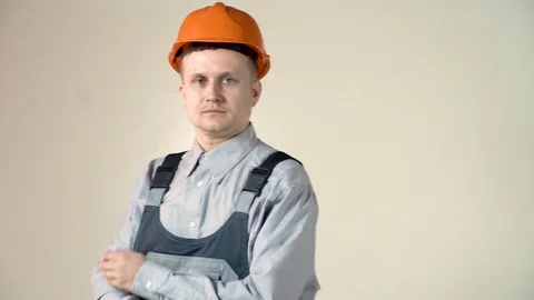 Successful engineer and orange helmet with folded arms on grey background. Stock Footage 102777687