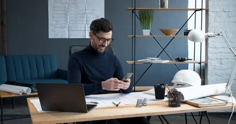 Successful Engineer is sitting in Loft Office, using Smartphone. Young Vídeo Stock 126161551