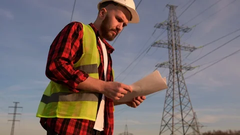 Successful engineers stand against the power pole on the blue background Stock Footage 128122020