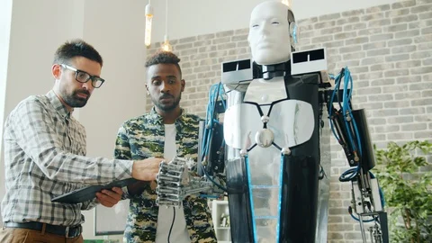Successful engineers testing cool robot in laboratory using tablet indoors Stock Footage 119577438
