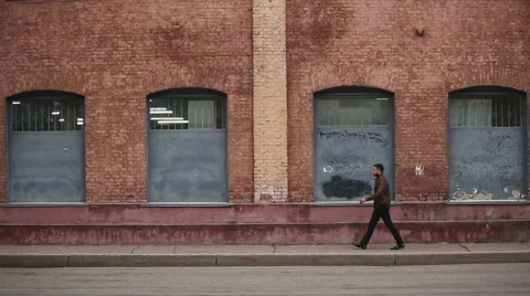 Successful happy man goes on a background of a brick wall of an old factory Stock Footage 44463458