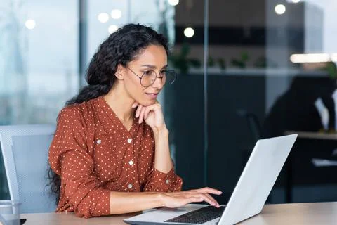 Successful Indian woman developer programmer working inside modern office, using Photos