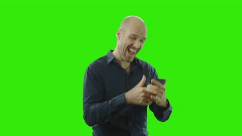 Successful man is cheering at his mobile phone in front of a greenscreen Stock Footage 166513431