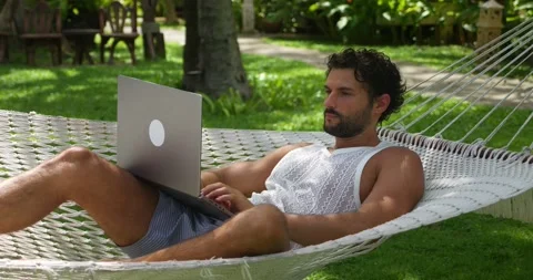 Successful man developer, programmer turns on laptop while chilling in a hammock Stock Footage 222135248