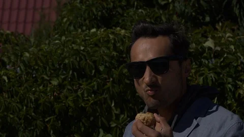 Successful man drinks from a paper cup and eats cookies on a sunny street Stock Footage 96760976