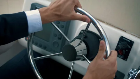 Successful man in a jacket rotates the steering wheel of his yacht Video stock 102664237