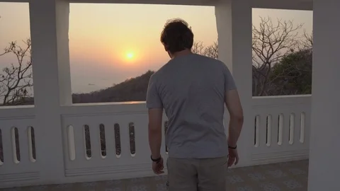 Successful Man Looking at Sunset Over Ocean From Luxury Mansion on Top of Hill Stock Footage 126575511