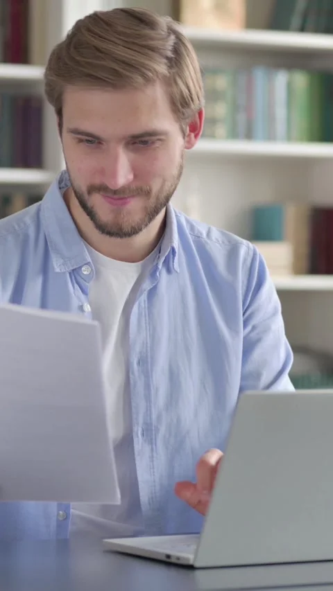 Successful Man Reading Documents while using Laptop, Vertical Video Stock Footage 339578237