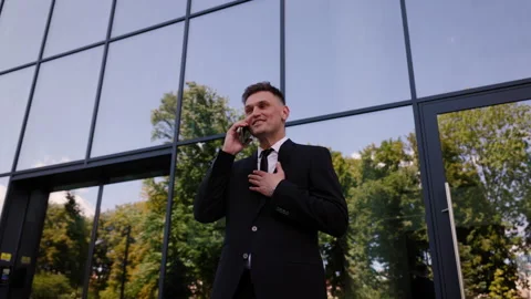 Successful man talking on smartphone outside an office building. Elegant Stock Footage 280612483