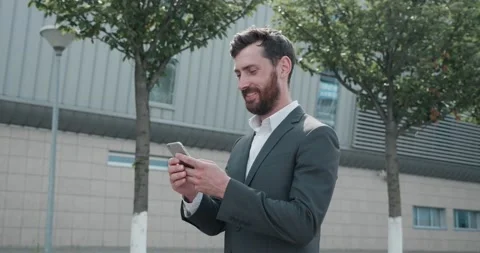 Successful Man Walking down the street Reading and Typing something on his Phone Stock Footage 132999358