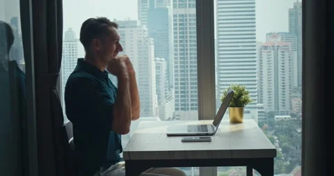Successful Man working remote with city skyline, remote tasks fueling flexible Stock Footage 312123516
