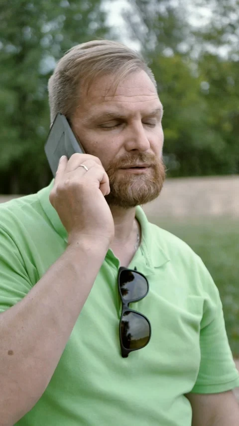 Successful middle-aged investor chatting on smartphone in park . Vertical Stock Footage 282963192