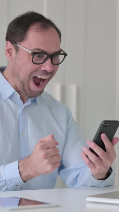 Successful Middle Aged Man Celebrating on Smartphone, Vertical Video 스톡 동영상 339584961